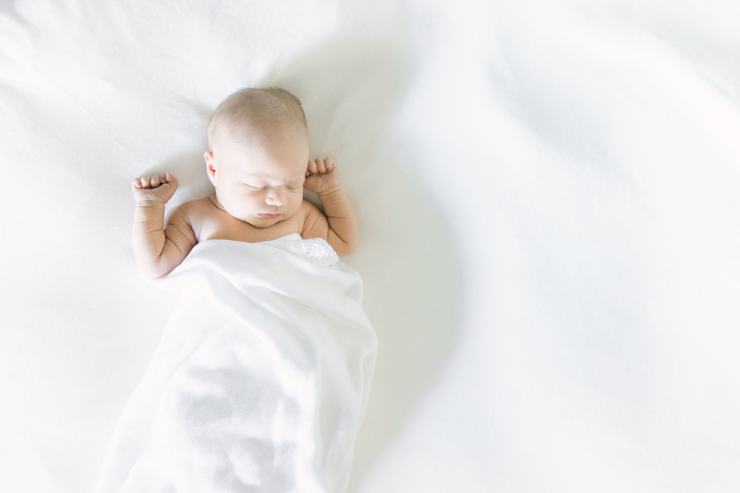 newborn baby lying in a white blanket
