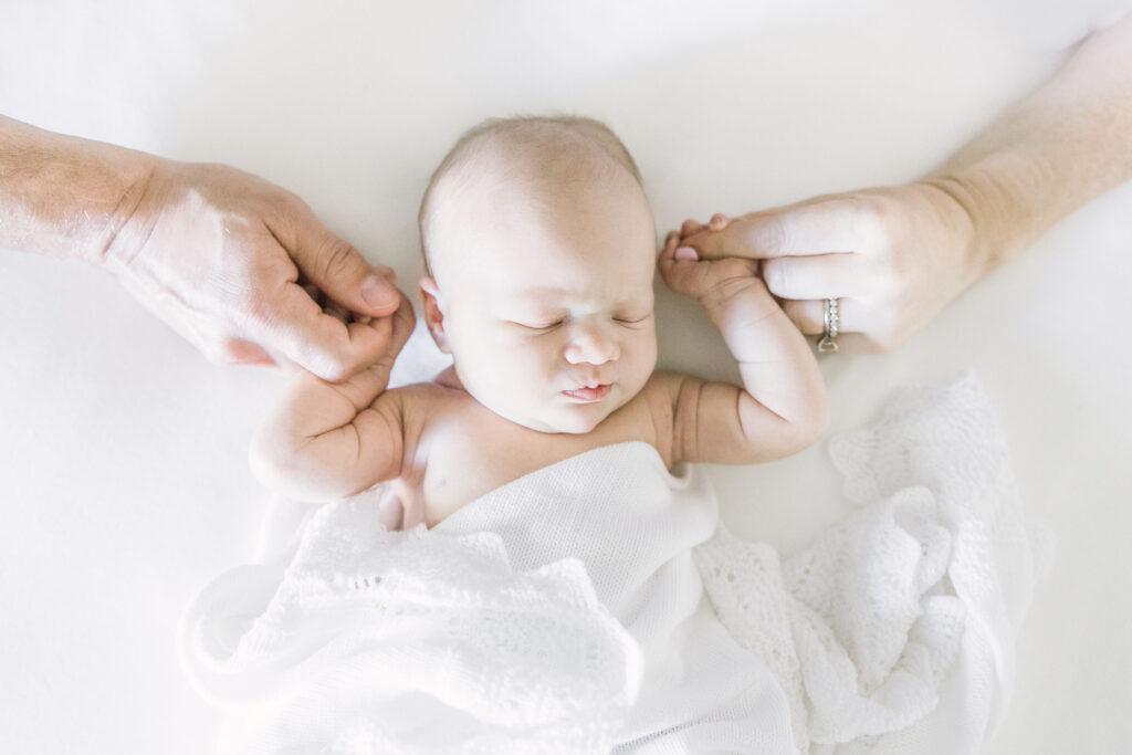 newborn baby resting between mom and dad