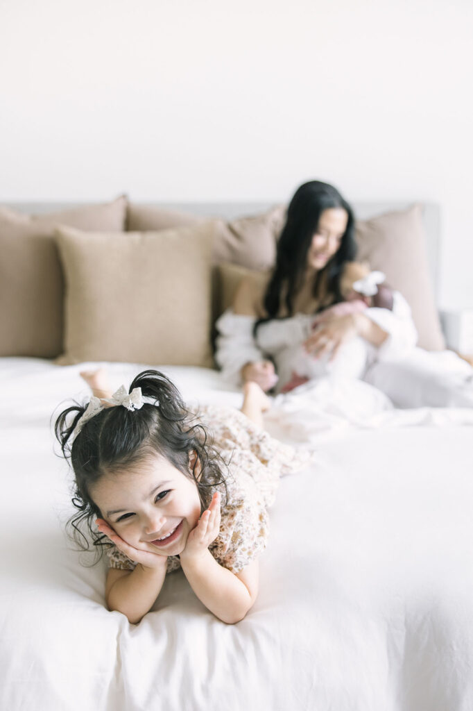 little girl playing on bed during a newborn photography session