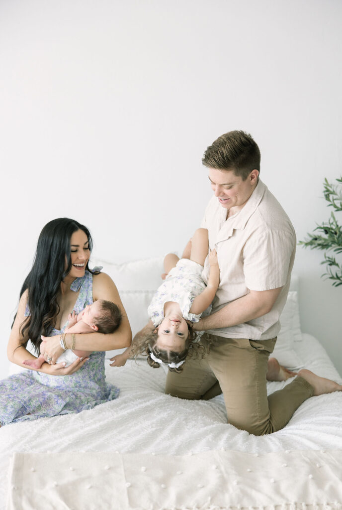 family playing with their little girls on a bed 