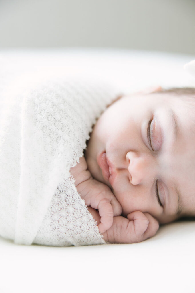 baby snuggling in a white swaddle